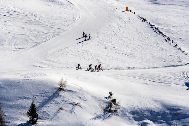 Hermosa vista de la gente en bicicleta y esquiar a través de montañas nevadas en el Tirol del Sur, Dolomitas, Italia
