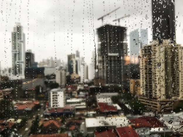 Hermosa vista de las gotas de lluvia rodando por la ventana y los rascacielos en la superficie