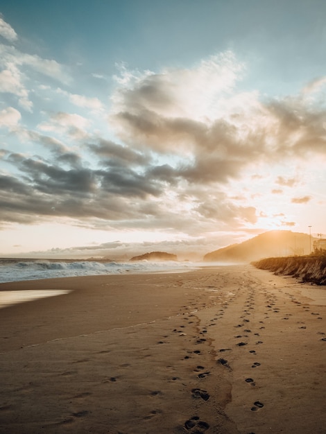 Hermosa vista de huellas en la arena durante el atardecer en la playa de Río de Janeiro.