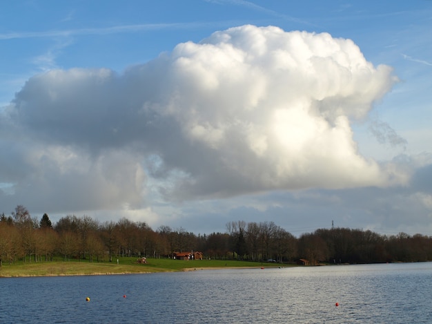 Foto gratuita hermosa vista del lago con un nublado cielo azul de fondo