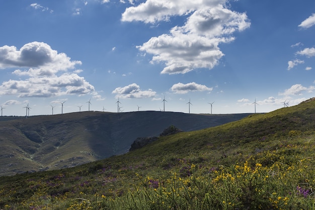 Hermosa vista de molinos de viento en una colina con un cielo azul nublado