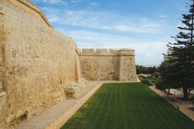 Hermosa vista del parque cerca del antiguo edificio de Mdina Gate en Malta bajo el cielo azul