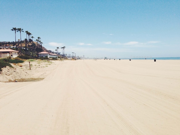 Hermosa vista de la playa de arena con edificios y montañas cerca de la orilla