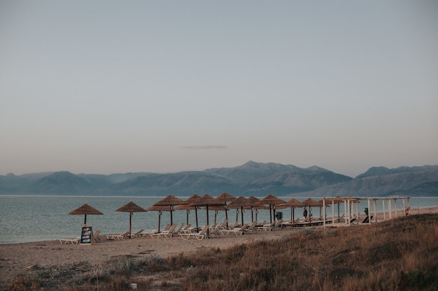 Hermosa vista de una playa con tumbonas bajo sombrillas de paja