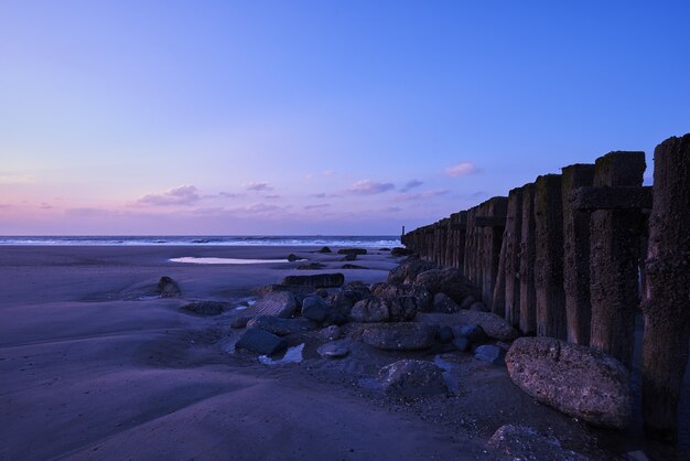 Hermosa vista de la puesta de sol con nubes púrpuras sobre la valla en la playa