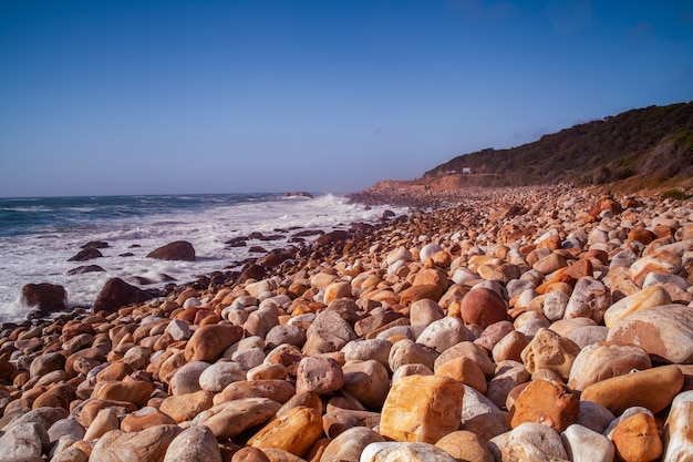 Hermosa vista de las rocas en la playa junto al mar bajo el cielo azul claro