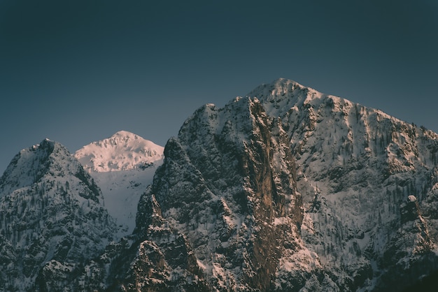 Hermosas altas montañas rocosas con una montaña nevada en el medio