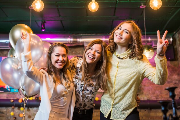 Hermosas amigas sonrientes que disfrutan de la fiesta en club nocturno