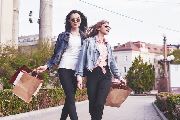 Hermosas chicas con bolsas de compras caminando en el centro comercial.