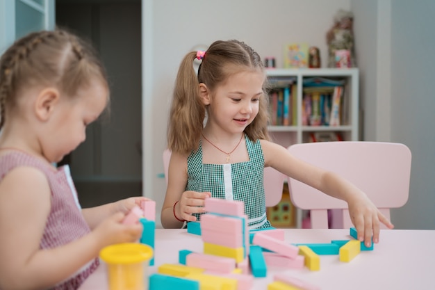 Hermosas chicas caucásicas jugando con bloques multicolores de madera