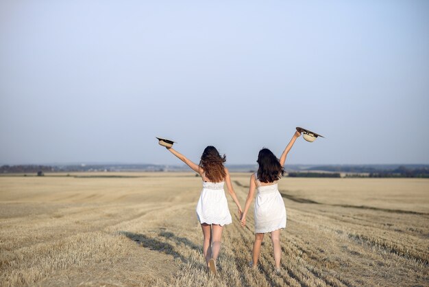 Hermosas chicas elegantes en un campo de trigo de otoño