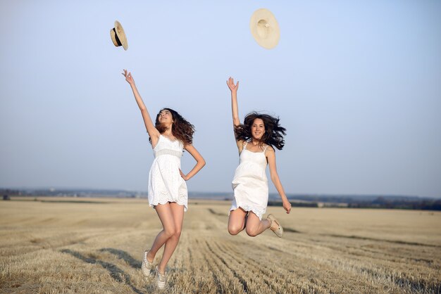 Hermosas chicas elegantes en un campo de trigo de otoño