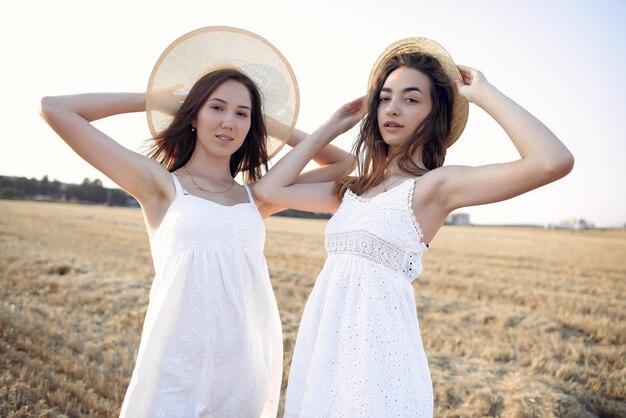 Hermosas chicas elegantes en un campo de trigo de otoño