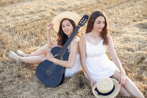 Hermosas chicas elegantes en un campo de trigo de otoño