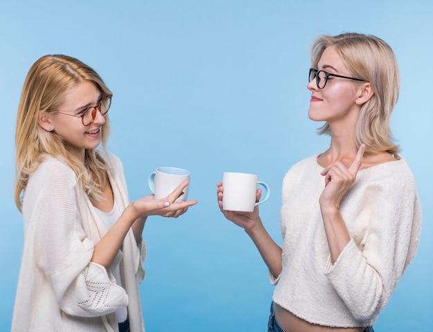 Hermosas chicas jóvenes con tazas de café