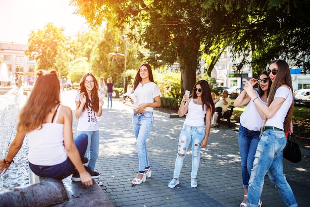 Hermosas chicas jóvenes tomando fotos en el árbol en un día soleado