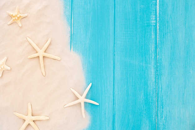 Hermosas estrellas de mar con arena sobre fondo azul de madera