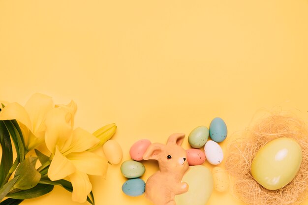 Hermosas flores de lirio con huevos de Pascua y nido sobre fondo amarillo