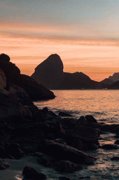 Hermosas formaciones rocosas cerca del mar con la puesta de sol en Río de Janeiro