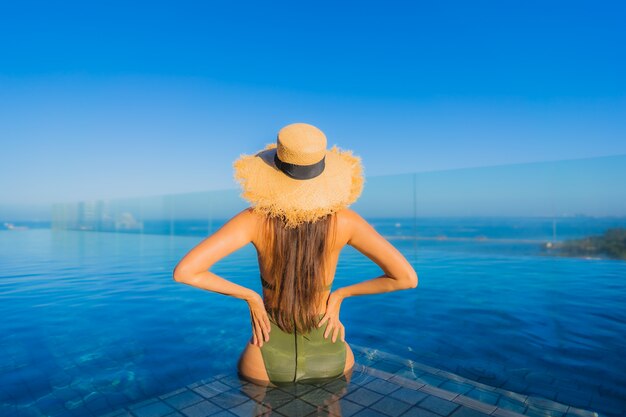 Hermosas jóvenes asiáticas sonrisa feliz relajarse en la piscina al aire libre en el hotel resort para viajar en vacaciones