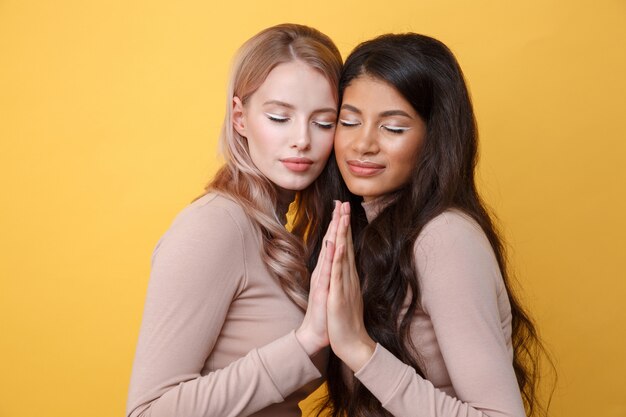 Hermosas jóvenes dos damas posando sobre pared amarilla