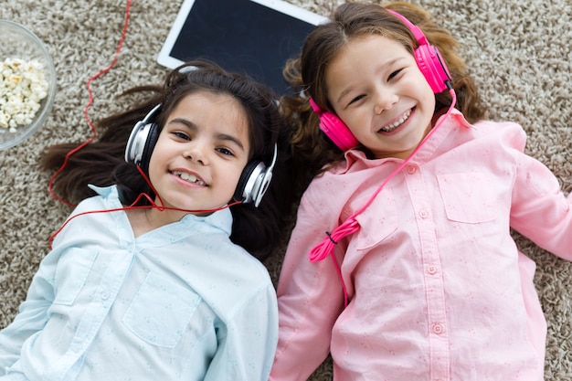 Foto gratuita hermosas jóvenes hermanas escuchando música con tableta digital a