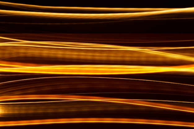 Foto gratuita hermosas líneas doradas vuelan en la oscuridad