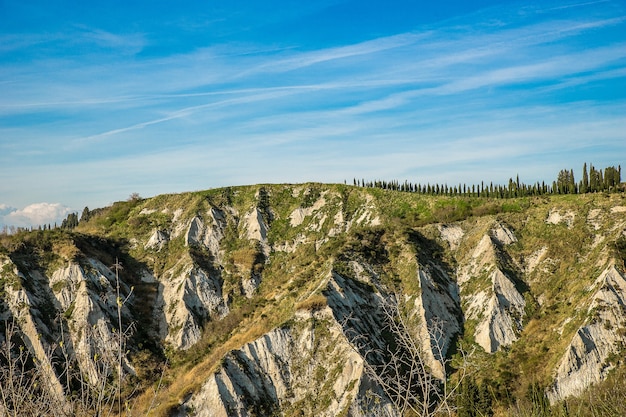 Hermosas montañas cubiertas de árboles y pasto bajo las increíbles nubes en el cielo