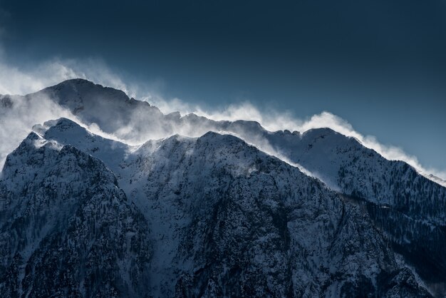 Hermosas montañas nevadas y nebulosas con nieve que sopla el viento