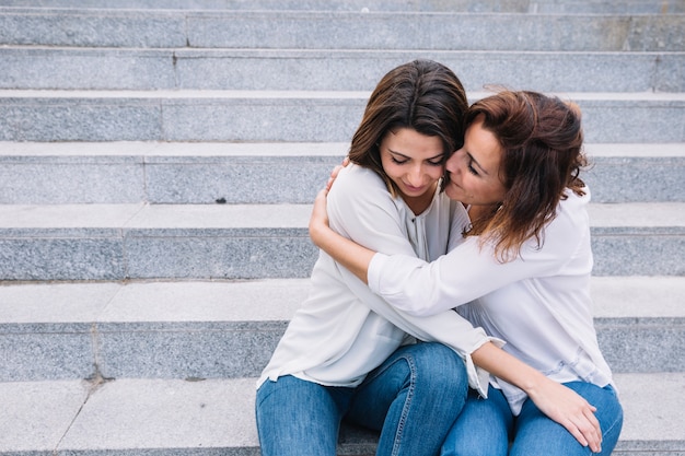 Foto gratuita hermosas mujeres abrazándose en las escaleras