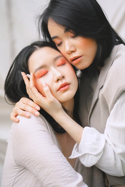 Hermosas mujeres abrazándose con los ojos cerrados durante el día.