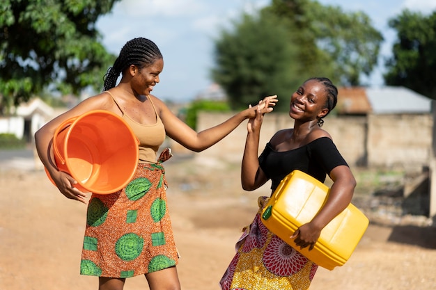 Foto gratuita hermosas mujeres africanas divirtiéndose mientras buscan agua