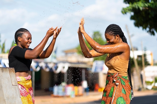 Foto gratuita hermosas mujeres africanas divirtiéndose mientras buscan agua