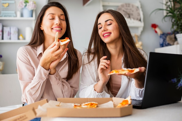 Hermosas mujeres comiendo pizza en casa