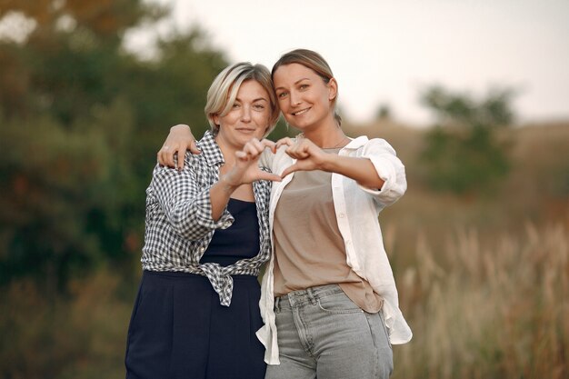 Hermosas mujeres elegantes en un campo de trigo de otoño