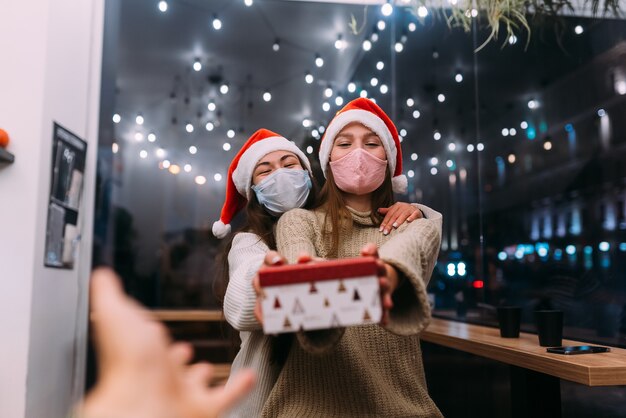 Hermosas mujeres jóvenes dan caja de regalo en el café