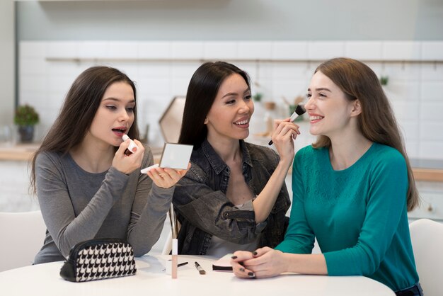 Hermosas mujeres jóvenes probando accesorios de maquillaje