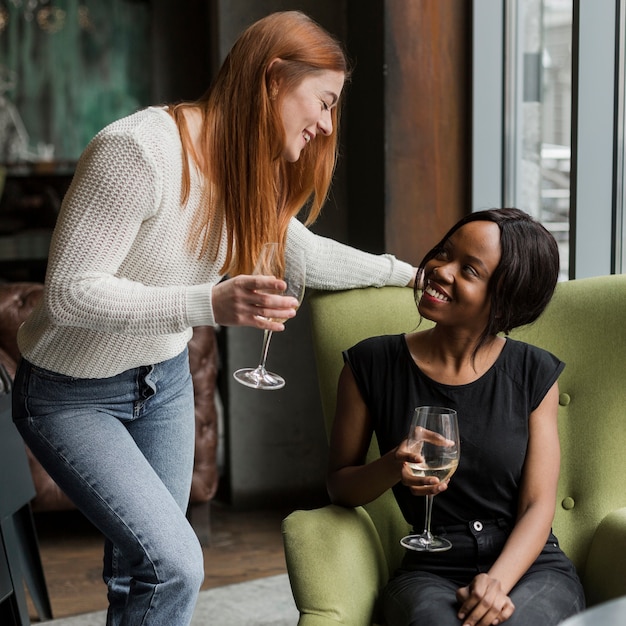 Hermosas mujeres jóvenes tomando vino juntos