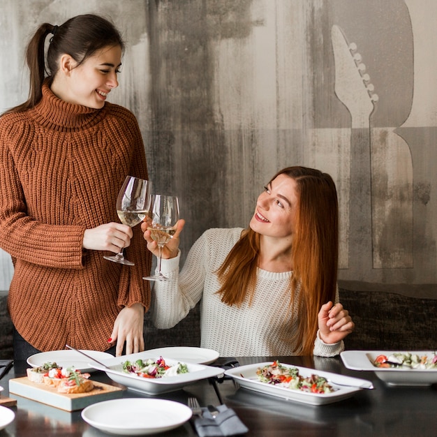 Hermosas mujeres jóvenes tostado copas de vino