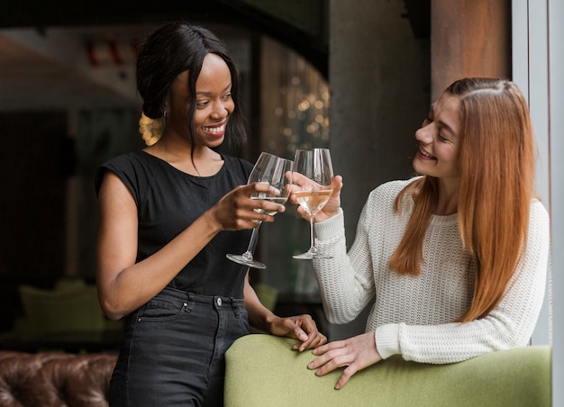 Hermosas mujeres jóvenes tostado copas de vino