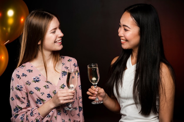 Hermosas mujeres mirándose y sosteniendo copas de champán