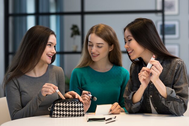 Hermosas mujeres probando accesorios de maquillaje