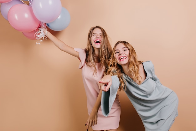 Hermosas mujeres riendo sosteniendo un montón de globos con los ojos cerrados