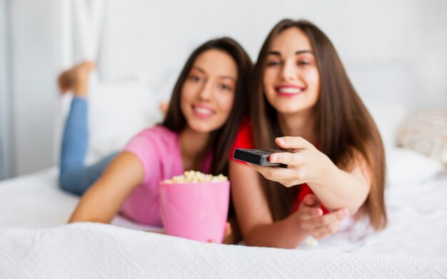 Hermosas mujeres sentadas en la cama y comiendo palomitas de maíz