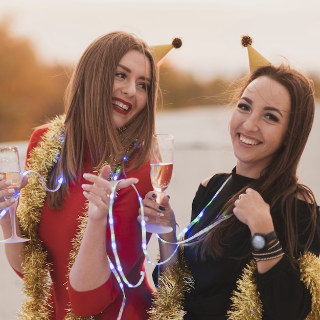 Foto gratuita hermosas mujeres sosteniendo copas de champán y lámparas en la fiesta en la azotea