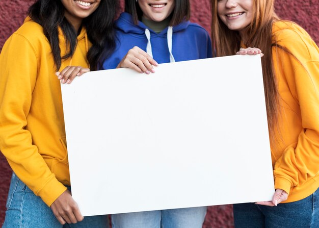 Hermosas mujeres sosteniendo una tarjeta en blanco