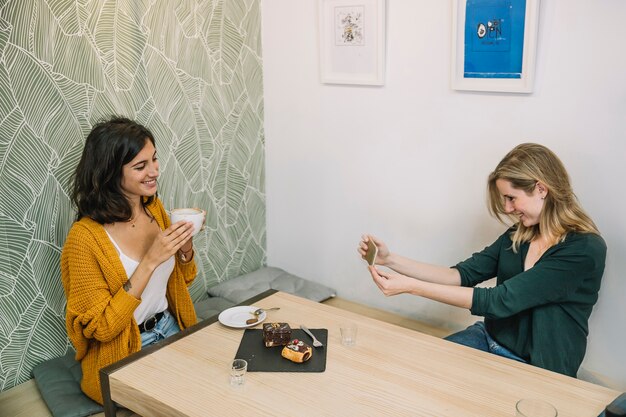 Hermosas mujeres tomando fotos en café