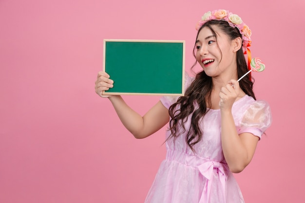 Hermosas mujeres vestidas con vestidos de princesa rosa sostienen un tablero verde sobre un rosa.