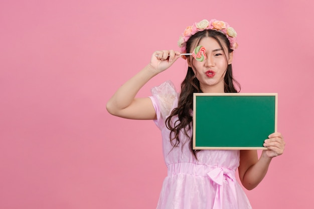 Hermosas mujeres vestidas con vestidos de princesa rosa sostienen un tablero verde sobre un rosa.