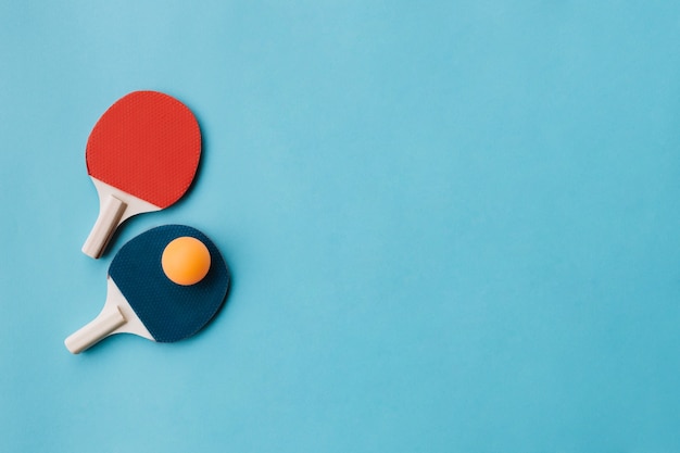 Foto gratuita hermosas raquetas de ping pong con pelota en azul subterráneo